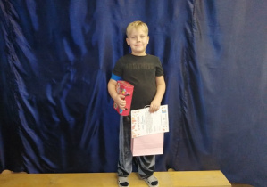 Chłopiec stoi z dyplomem i nagroda za konkurs